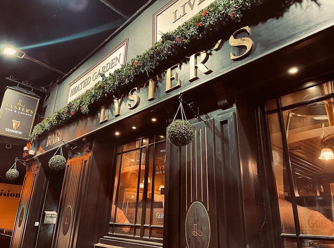 Lyster's at dusk: the black-and-gold façade on Harold's Cross Road, warm light in the windows